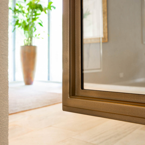 Detail van een bronzen stalen deur met glas, verfijnde afwerking en moderne uitstraling.